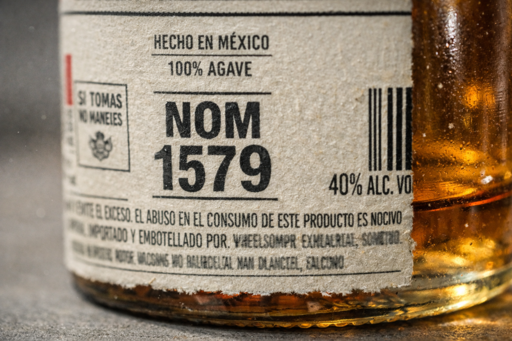 Close-up of tequila bottle back label showing NOM number regulatory code for distillery identification
